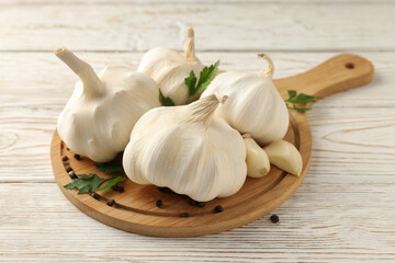 Board with garlic, parsley and pepper on wooden background