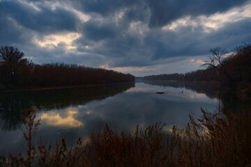a beautiful autumn landscape in the evening - forest with river and cloudy sky
