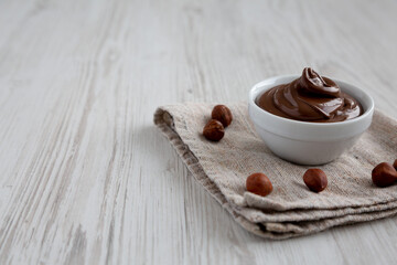 Homemade Chocolate Hazelnut Spread in a Bowl on a white wooden background, side view.