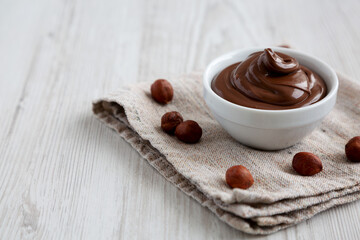 Homemade Chocolate Hazelnut Spread in a Bowl on a white wooden background, side view. Space for...