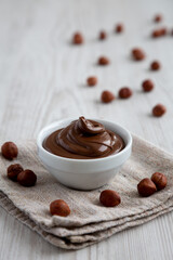 Homemade Chocolate Hazelnut Spread in a Bowl on a white wooden surface, side view.