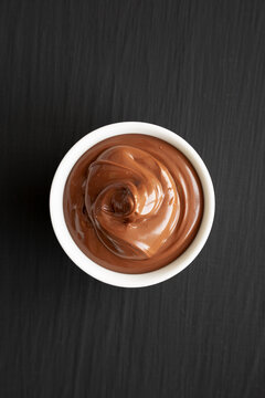 Homemade Chocolate Hazelnut Spread in a Bowl on a black background, top view. Flat lay, overhead, from above.