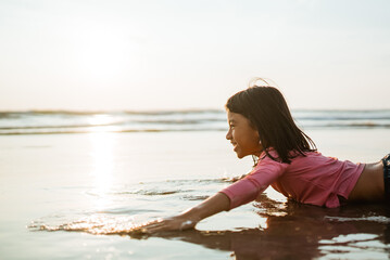 Fototapeta na wymiar asian child playing laying in the beach enjoy the sunset