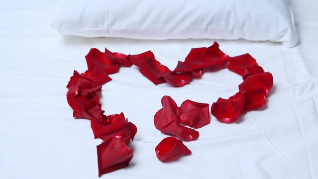 Heart of red rose petals on a white bed. The concept of romantic relationships. Congratulations on the holiday.