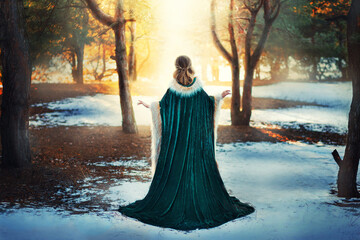 Fantasy woman walks in winter forest. Princess girl. Green long vintage coat fur. Mystical image...