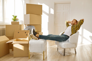 Man rest on wrapped chair among boxes