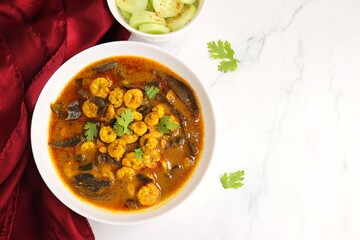 Tangy and spicy Shrimp curry. Tiny prawns curry made using dried mango and Indian spices. garnished with coriander and served with cucumber slices. Copy space.