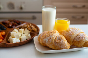 Delicious breakfast with fresh croissants, orange juice and a glass of milk.