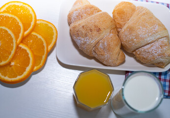 Delicious breakfast with fresh croissants, orange juice and a glass of milk.