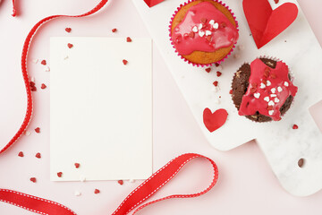 Three homemade white and chocolate muffins with red frosting and heart-shared red and white sugar...