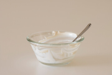 Empty yogurt bowl, with a spoon in it, isolated on a white background. Creamy plant-based yogurt, dairy-free vegan food, ketogenic diet, and healthy nutrient-packed snack concept.
