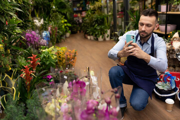man taking pictures of potted plants with mobile phone