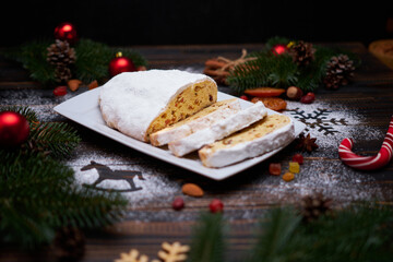 Sliced Traditional Christmas stollen cake with marzipan and dried fruit on wooden background