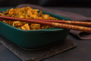 Vegetable stew with green beans and cauliflower in a green ceramic bowl.