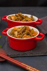 Vegetable stew with green beans and cauliflower in a red ceramic bowl.