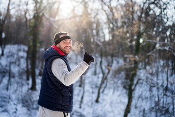 Adult man is ready for exercising in park in wintertime. He is smiling and showing thumb up.