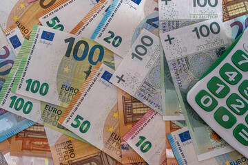 Fototapeta na wymiar banknotes of new euros and Polish zlotys in different scattered on the table calculator nearby.
