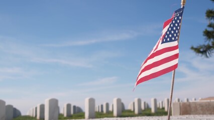 Tombstones and american flag, national memorial cemetery, military graveyard in USA. Headstones or gravestones, green grass. Respect and honor for armed forces soldiers. Veterans and Remembrance Day.