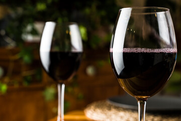 Wine tasting. A glass of red wine on the background of a restaurant table with bottle at an evening dinner or event party.