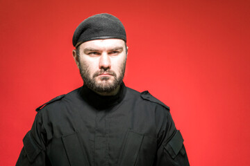 Obraz premium Male guard in black uniform and cap. Bodyguard. Defender of the law and order. Military. Mercenary. Handsome brutal man.