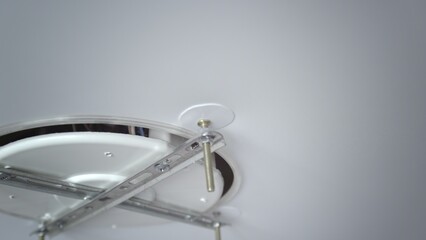 A close-up of the hands of an unrecognizable man inserting the base for mounting a ceiling light. Repair