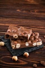 Delicious milk chocolate bars with nuts close up. Stack of chocolate slices Hazelnut pieces tower. Sweet food photo concept