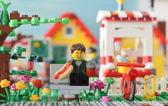 Editorial illustrative image of lego minifigure in park with hot dog in hand. Popular brand of plastic toys.