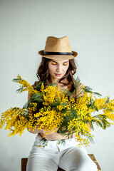 Beautiful woman with a bouquet of mimosa in spring