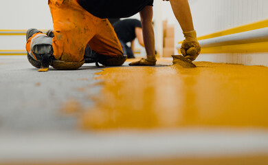 Professional construction worker applying floor paint or a new layer for a epoxy cast coating floor