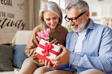 Romantic senior man congratulating happy wife on Valentines Day at home