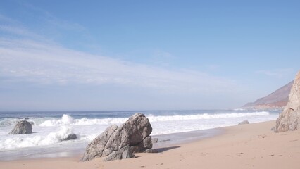 Big huge pacific ocean waves crashing on sandy shore, empty Garrapata beach, California coast, Big Sur nature landscape, USA. Splashing water tide sea foam, mountains in foggy misty weather. Highway 1