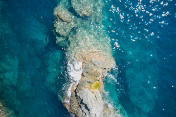 Aerial view of sea waves and fantastic Rocky coast, Italy. Rock and sea. Clear amazing azure colour sea water with granite rocks in beach, Italy. Stone rock close up in the sea water.