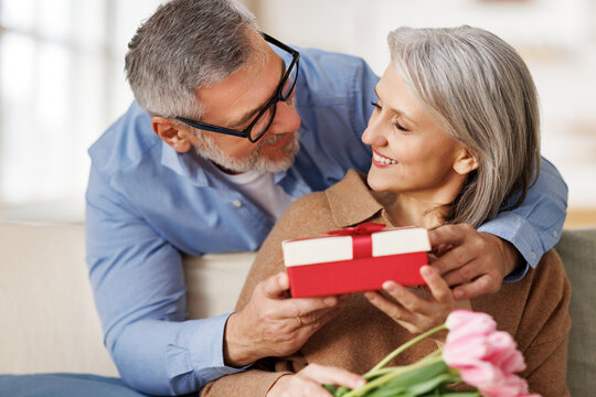 Romantic senior man congratulating happy wife on Valentines Day at home