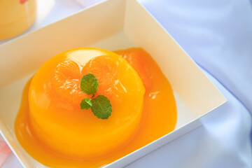 An orange cake with orange topping and pepermint on a white table.