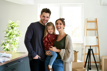 Portrait of happy caucasian family with daughter in a new apartment