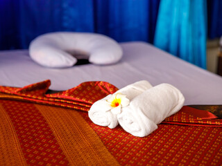 Empty massage bed in spa with pillow, towels and plumeria flowers Thai traditional style...