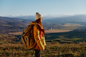 woman traveler in a yellow jacket in a hat backpack travel mountains Fresh air