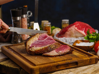 Pieces of raw farm meat prepared by the chef's hands for juicy steaks on a wooden cutting board. Lots of ingredients. Focus in the foreground. Restaurant menu, hotel, cafe, culinary blog, advertising