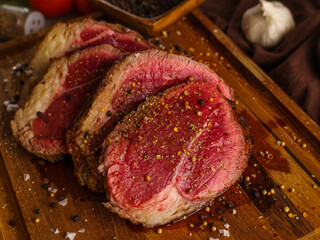 Raw pieces of meat sprinkled with spices on a wooden cutting board. Cooking beef steaks. Organic farm meat. Restaurant, hotel, cafe, home cooking, recipes. There are no people in the photo.