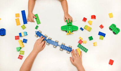 Close up kid boy hands playing with toy bricks on white background.
