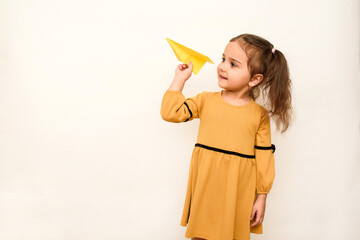 Little girl is holding a paper airplane on a white background.