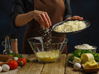 Preparation of cheese filling by the hands of a professional chef. The concept is cooking pizza, pie. A lot of ingredients on a wooden table - vegetables. greenery. spices. eggs. A restaurant. hotel.