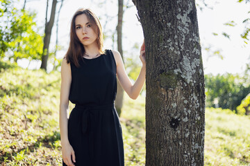 Portrait of young woman in black dress in the park.