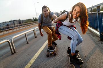 Group of happy teen people hang out together and enjoying skateboard outdoors.