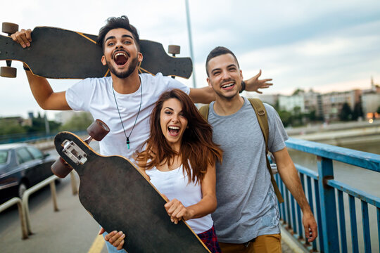 Group of happy teen people hang out together and enjoying skateboard outdoors.