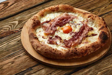 Carbonara pizza with bacon and egg on wooden background