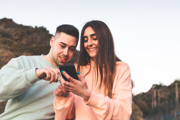 Young caucasian couple using a smartphone on the nature.