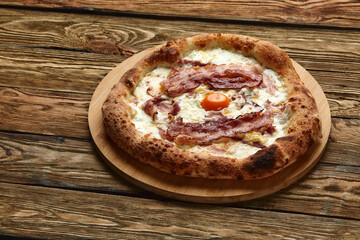 Carbonara pizza with bacon and egg on wooden background
