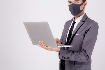 Young asian business man in face mask using laptop computer isolated on white background, quarantine and epidemic covid-19, businessman work from home for health, social distancing, new normal.