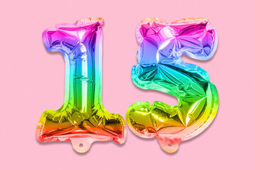Rainbow foil balloon number, digit fifteen on a pink background. Birthday greeting card with inscription 15. Anniversary concept. Top view. Numerical digit. Celebration event, template.